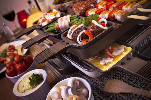 44321410 - swiss raclette or the dutch variant 'gourmetten'. a table filled with ingredients for a dish that is usually served on celebratory evenings like christmas or new years eve in the netherlands.