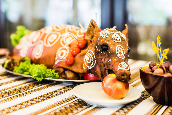 62309616 - decorated and roast suckling pig with an apple in his mouth on a white plate on banquet